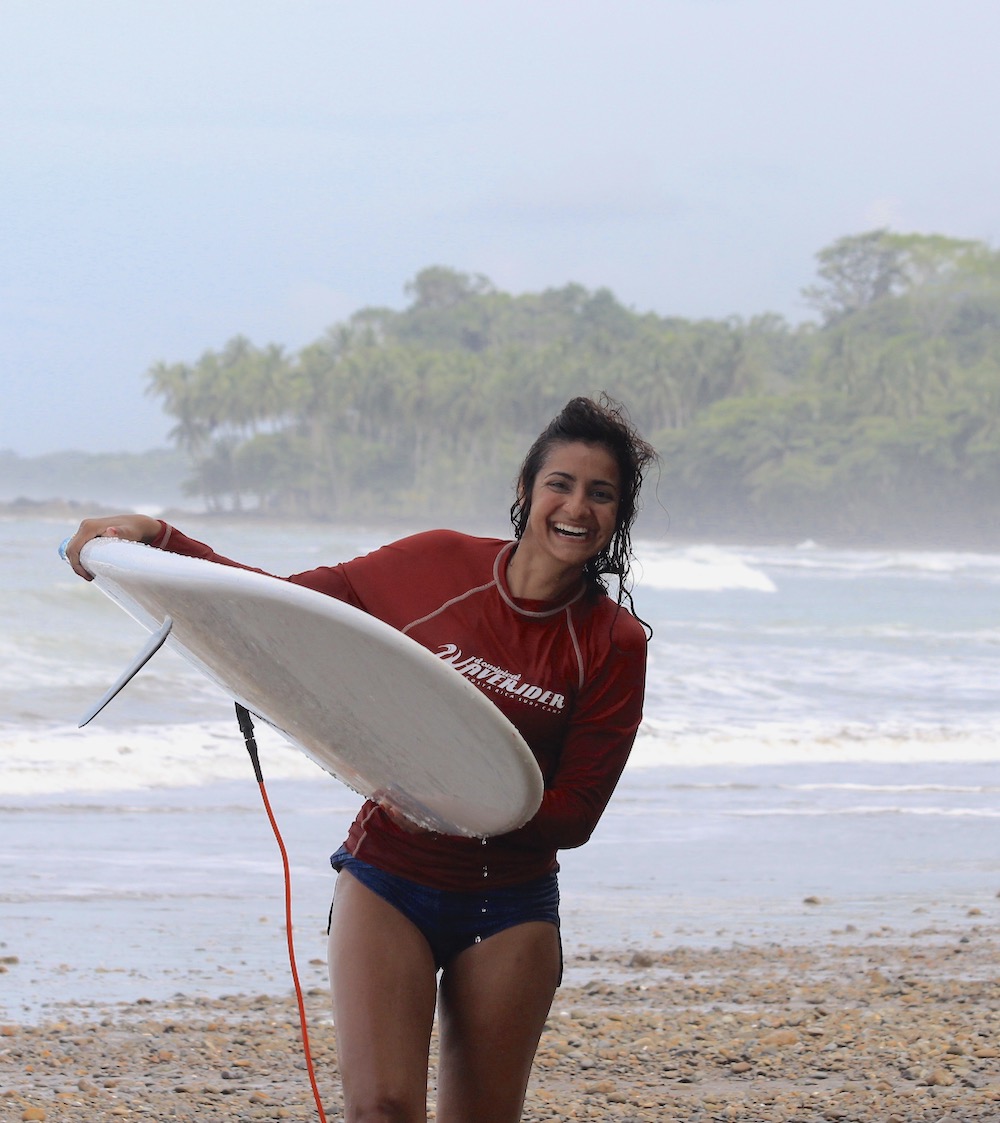 Sahana carrying a surfboard