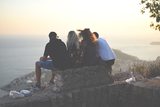 Group of friends sitting closely on bench overlooking view